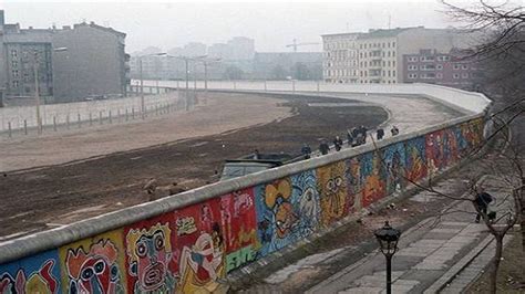 A picture of the Berlin Wall, a physical barrier that divided East and West Berlin