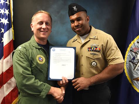 A Navy recruiter in uniform shaking hands with a young recruit