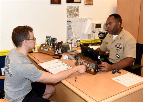 A Navy recruiter in uniform shaking hands with a young recruit