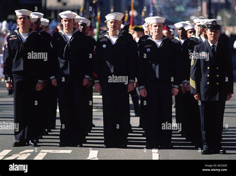 A group of sailors in formation, with the American flag in the background