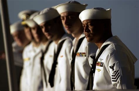 A group of sailors in uniform, with the Navy's insignia