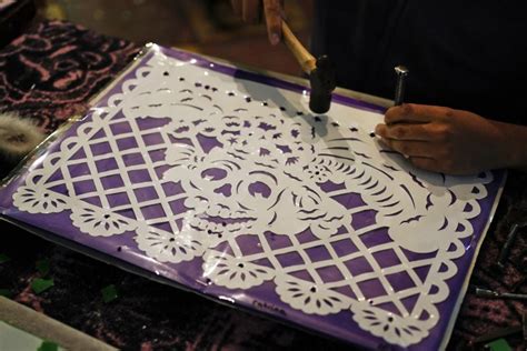 A traditional papel picado design featuring skulls and flowers