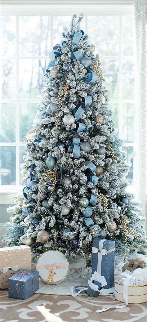 A blue Christmas tree decorated with a bow tree topper and ribbon garland