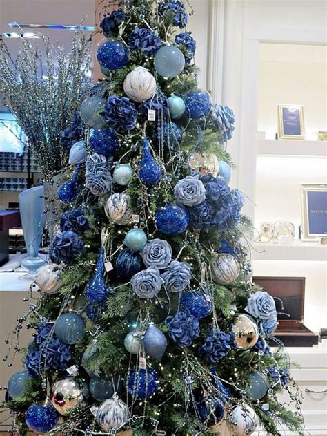 A blue Christmas tree decorated with glittering ornaments and tinsel garland