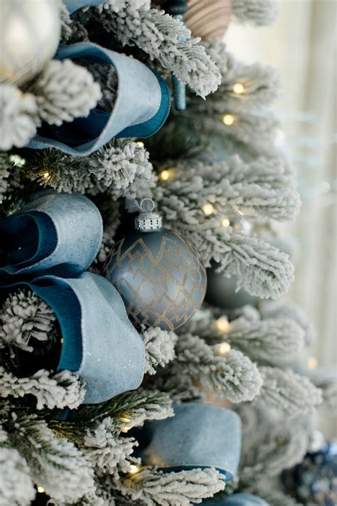 A blue Christmas tree decorated with glass ball ornaments and glittering garland