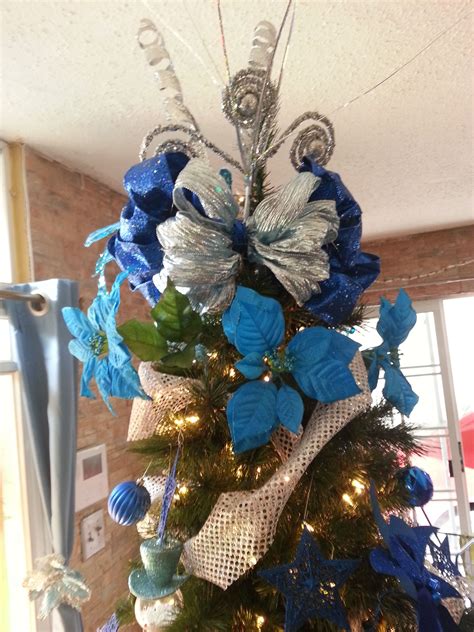 A blue Christmas tree decorated with a star tree topper and glittering garland