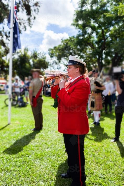 A bugle player performing during the day, in a park