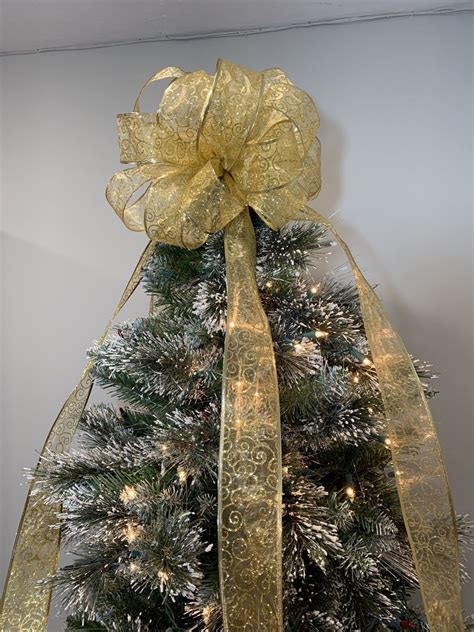 A majestic Christmas tree adorned with a stunning gold bow at its apex