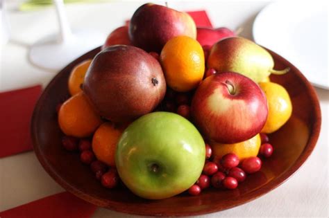 Person creating a fruit bowl with various fruits