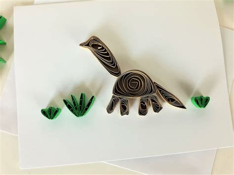 A quilled dinosaur design created using rolled paper strips