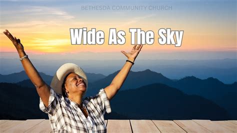 Image of a person standing in a field, arms outstretched, looking up at the sky