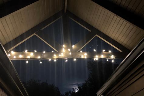 A handyman hanging Christmas lights on a house