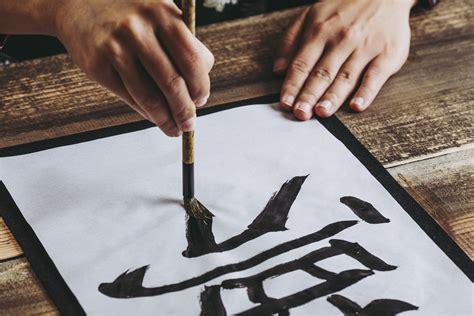 A brush pen writing Japanese characters on a paper