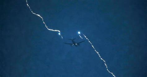 A plane flying through a stormy sky with lightning illuminating the clouds