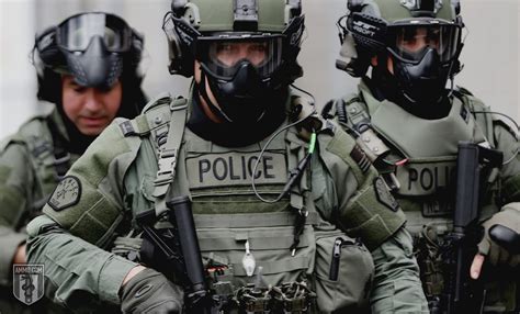 Image of a police officer in riot gear holding a military-style rifle