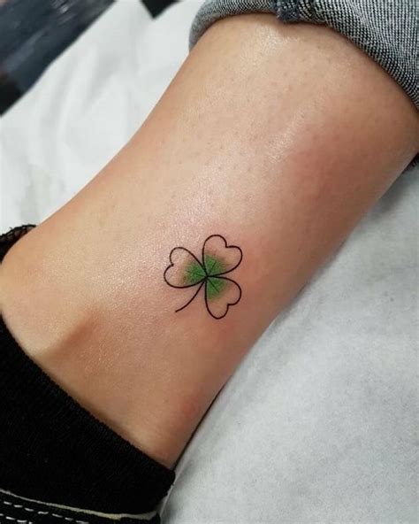 A small, minimalist shamrock tattoo on the wrist