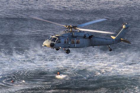 A Navy helicopter in flight, with a clear blue sky in the background.