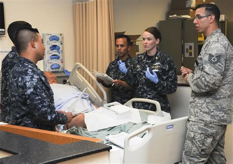 A Navy medic in action, with a hospital bed in the background.