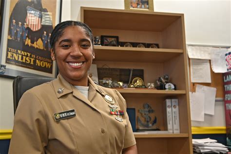 A person shaking hands with a Navy recruiter, with a Navy logo in the background.