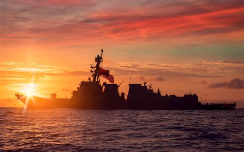 A Navy vessel at sunset, with a subtle horizon in the background.