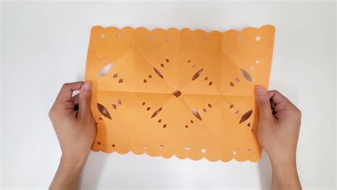 A photo of a person cutting out a papel picado design