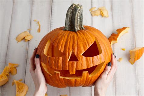 A person holding a whole pumpkin at a grocery store