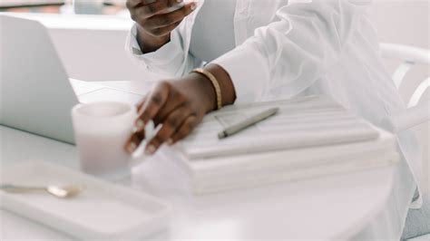 A person writing in a journal with a cup of coffee nearby