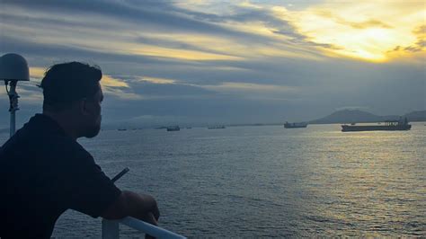 A photo of a seaman standing on the deck of a ship, with the sea stretching out behind him