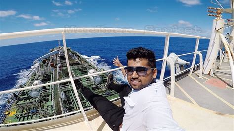 A photo of a seaman standing on the deck of a ship, with the sea stretching out behind him