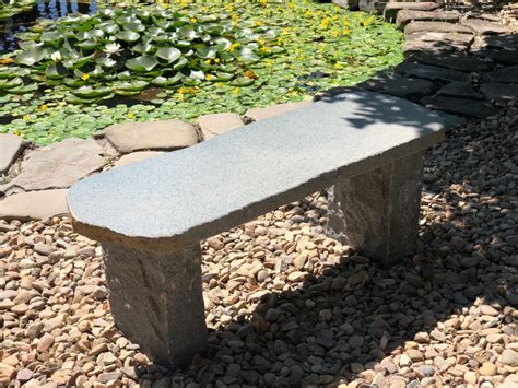 A stone bench with a plaque in a serene garden