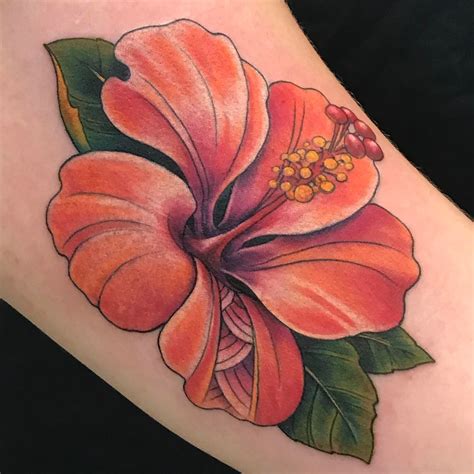 A tattoo artist at work, creating a Hawaiian flower design